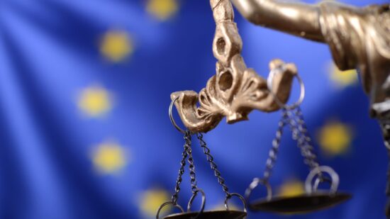 Scales of Justice, Justitia, Lady Justice in front of the European Union flag in the background.